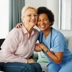 Older woman in a wheelchair embracing her in-home nursing nurse